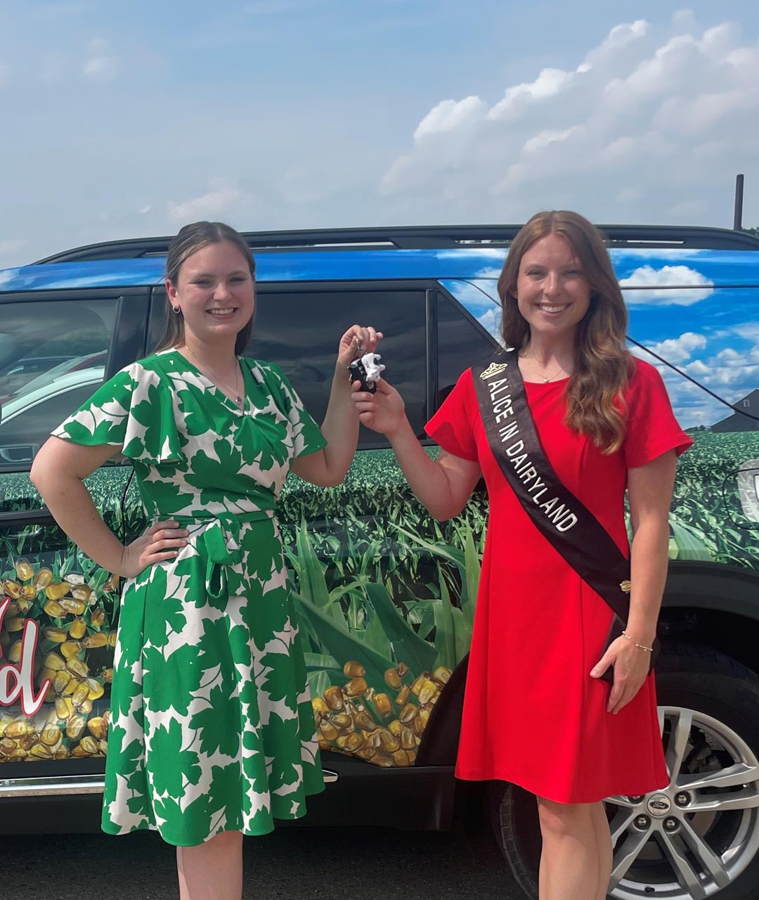 Photo of two women standing in front of the Alice in Dairyland car, holding car keys